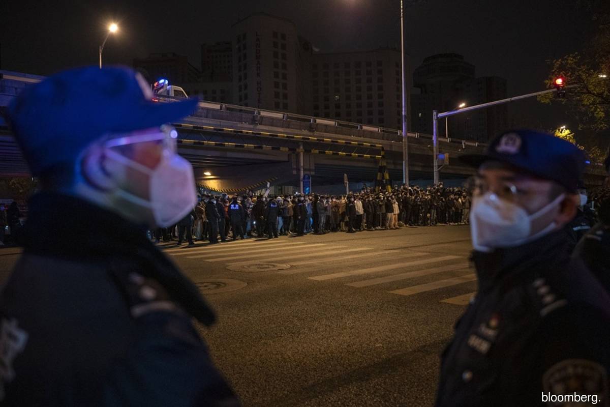 Police seen keeping watch during a protest against China's strict zero Covid measures in Beijing on Nov 28., 2022.